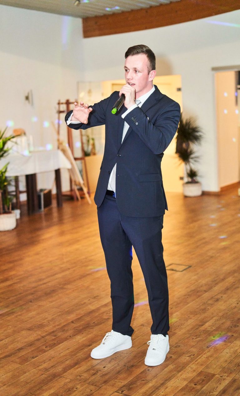 DJ Baumi bei einer Moderation DJ Baumi hat hier ein Mikrofon in der Hand und stellt sich nett bei den Gästen vor.